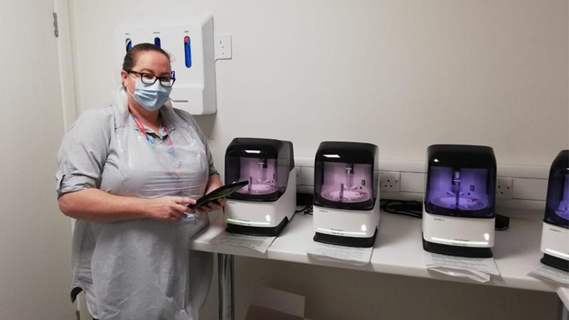 Student Donna Morris standing next to PCR COVID testing machines