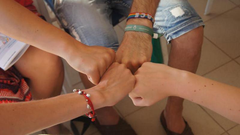 Four people bumping fists together
