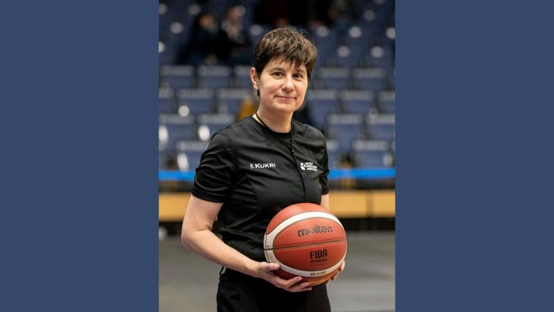Frances Kremarik in her British Wheelchair Basketball referee kit and holding a basketball
