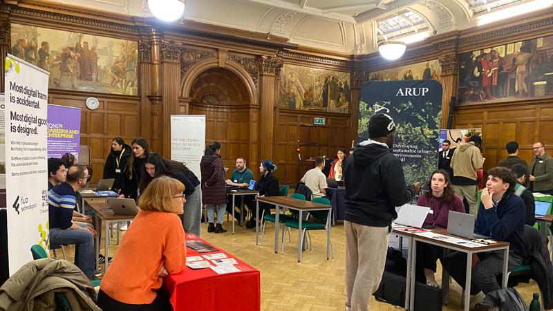 Photo of students participating in the Green Jobs Fair and speaking to various businesses at tables around a large room
