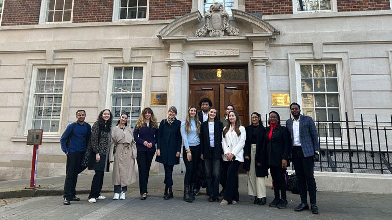 Students stand with Dr Frennhoff Larsen in front of the EU Delegation at Europe House.