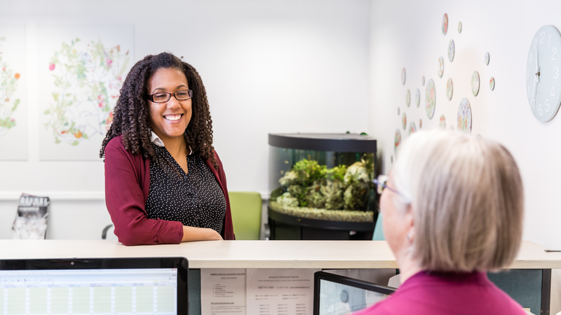 Image of a woman smiling over a reception desk