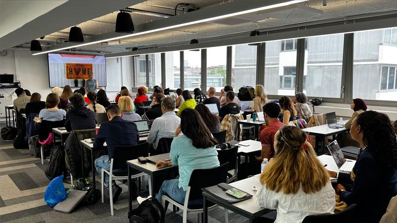 A talk is being delivered to a full room at the Rebel School x Netcompany workshop.