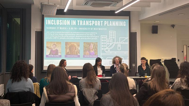 A photo of the panel in front of a projector reading INCLUSION IN TRANSPORT PLANNING with a description of the event.