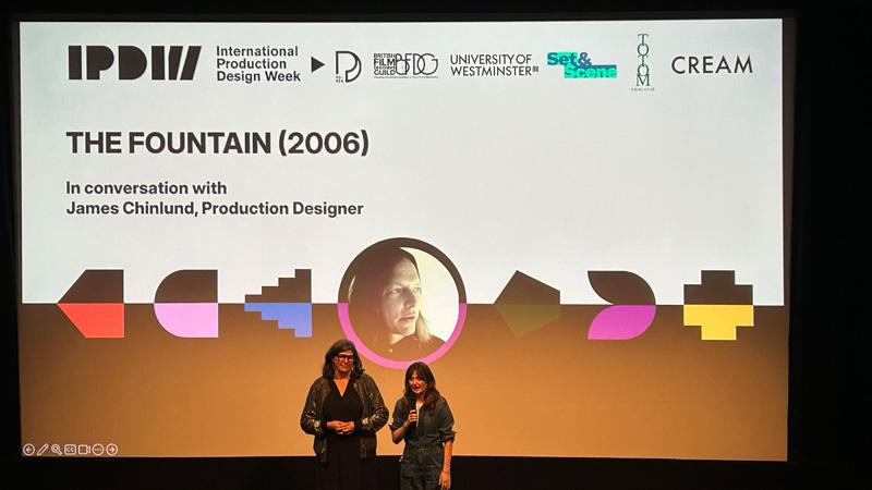 Photo of Jo Briscoe and Jane Barnwell opening the conference in front of a cinema screen displaying an intro slide for a screening of The Fountain (2006) in conversation with James Chinlund