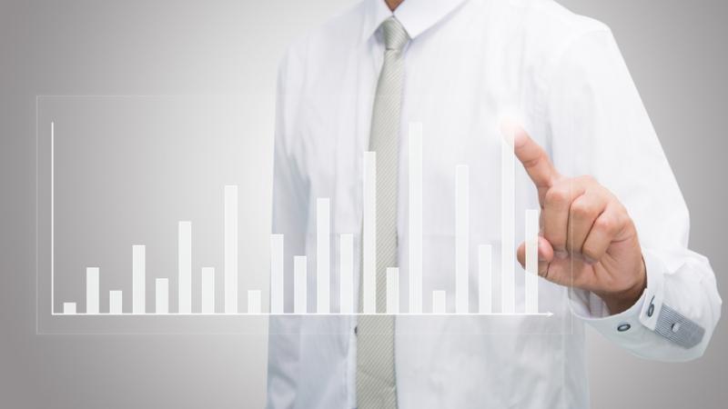 a man in a work shirt and tie pointing to a graph