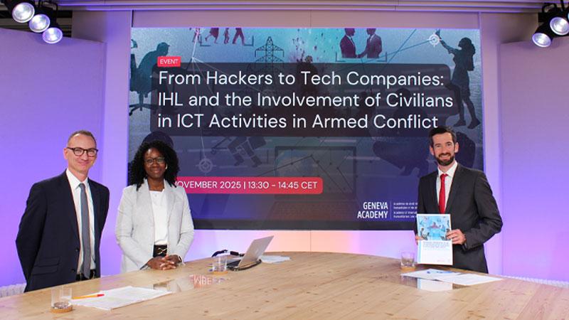 Marco Roscini sitting with co-presenters around a table in front of a projector screen which reads: From Hackers to Tech Companies: IHL and the Involvement of Civilians in ICT Activities in Armed Conflict.