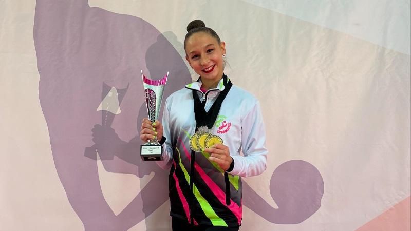Marfa Ekimova stands holding her trophy and three medals.