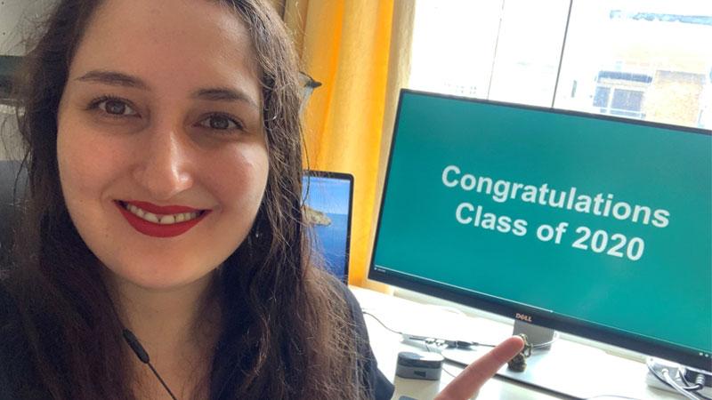 Westminster graduate Mariia Kogan in front of computer monitor with Class of 2020 presentation on screen