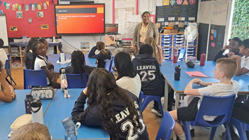 Photo of Merin Pereira delivering a school outreach session to primary school students