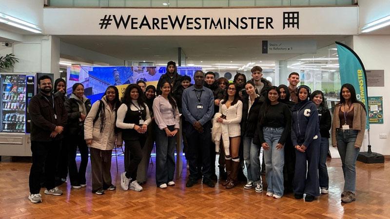 Group photo of NCC pupils and Westminster colleagues under a wall decal which reads: #WEAREWESTMINSTER