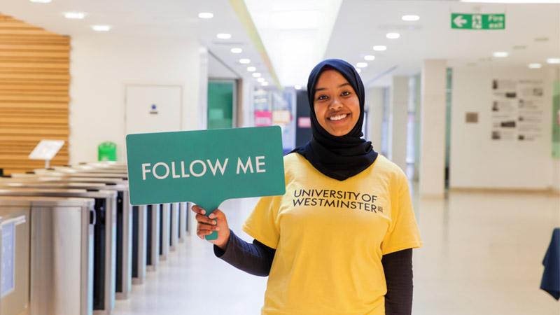 A student holding up a sign saying "Follow me"