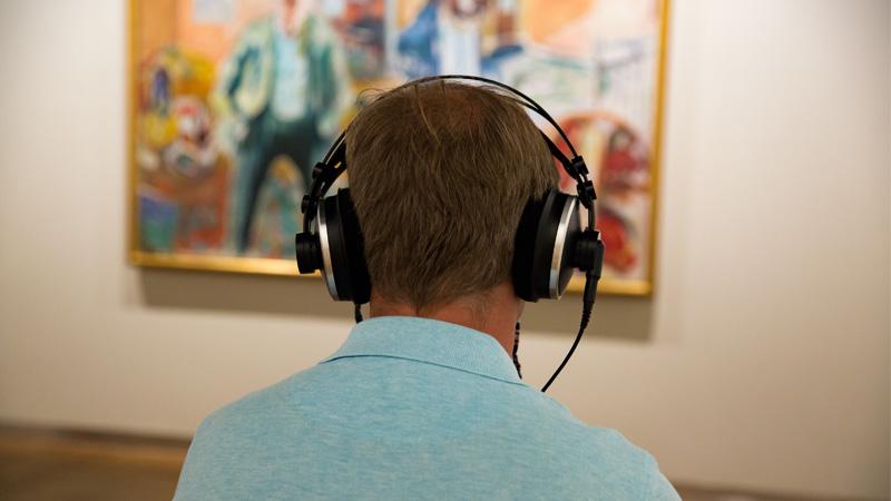 Person looking at art and listening to audio guide in museum