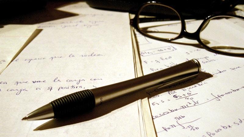 Pen and glasses placed on written pieces of paper