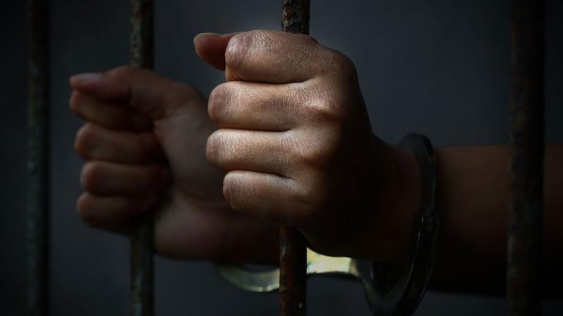 Hands holding prison cell bars
