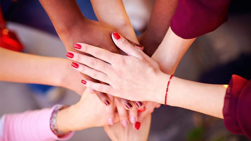 Pile of female multiracial hands in union sign.