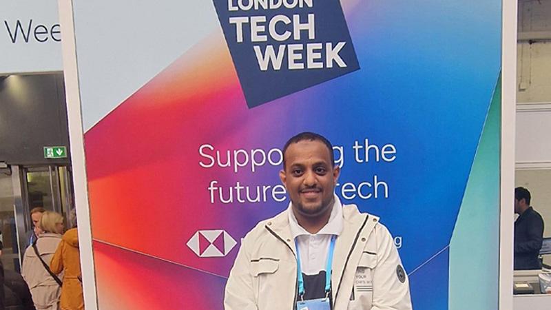 Photo of Semir Idris in front of a poster reading "London Tech Week"