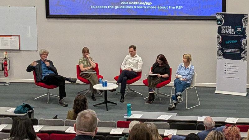 Steve Barnett (left) speaking on a panel with four other panellists