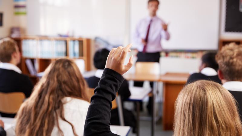 Student raising hand in classroom