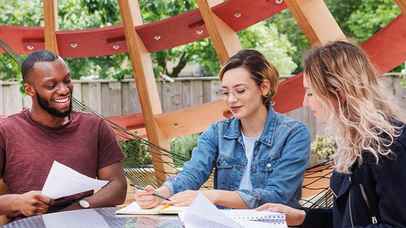 Students studying outside under a pavilion