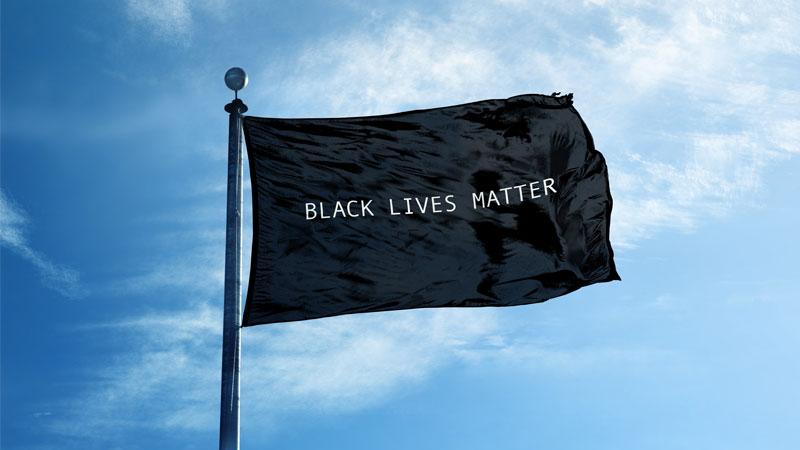 Black Lives Matter flag blowing against a blue sky