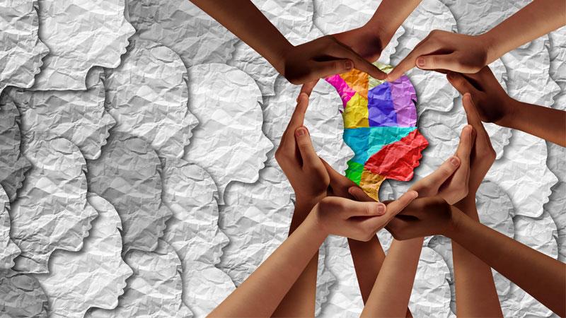 Image of children's head outlines with rainbow outline surrounded by hands in the shape of a heart