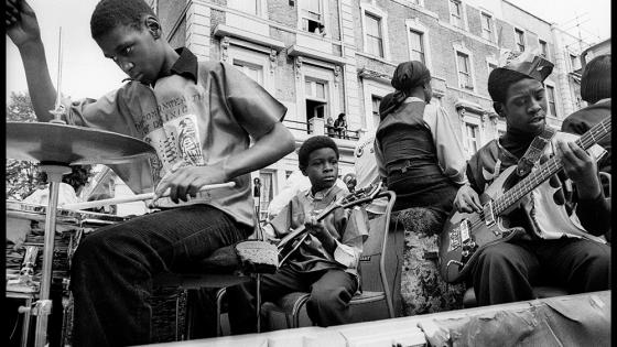 A black and white photograph of young people playing drums and guitars