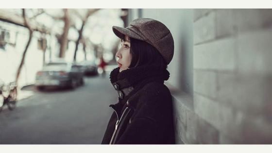 A woman standing against a wall.