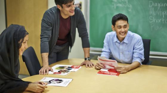 A group of IELTS students around a table with IELTS test materials