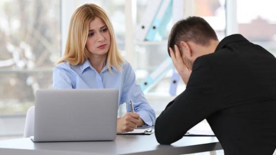A man with his head in his hands and a woman taking notes