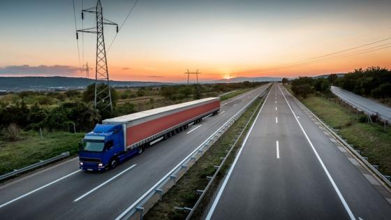 A truck driving on the motorway with the sunset in the bakground