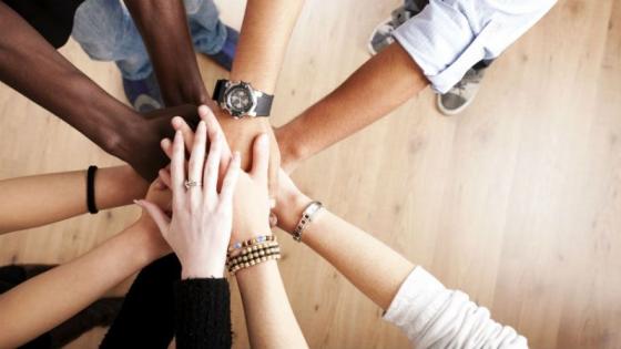 A group of people having their hands together, one above another