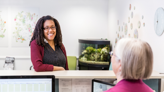 Image of a woman smiling over a reception desk