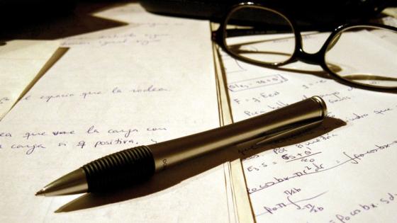 Pen and glasses placed on written pieces of paper