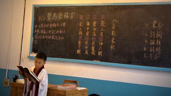 Child reading in front of a blackboard