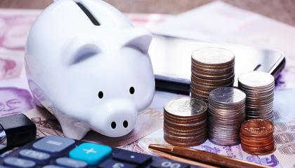 A money bank next to coins and a calculator.