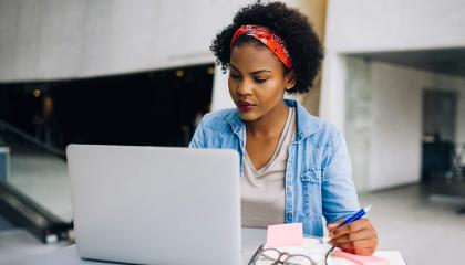 Woman working on laptop taking notes
